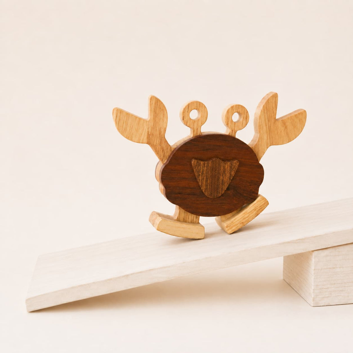 Handmade wooden crab ramp walker toy with a dark walnut body and pale beech legs, walking on a gently sloped wooden ramp.