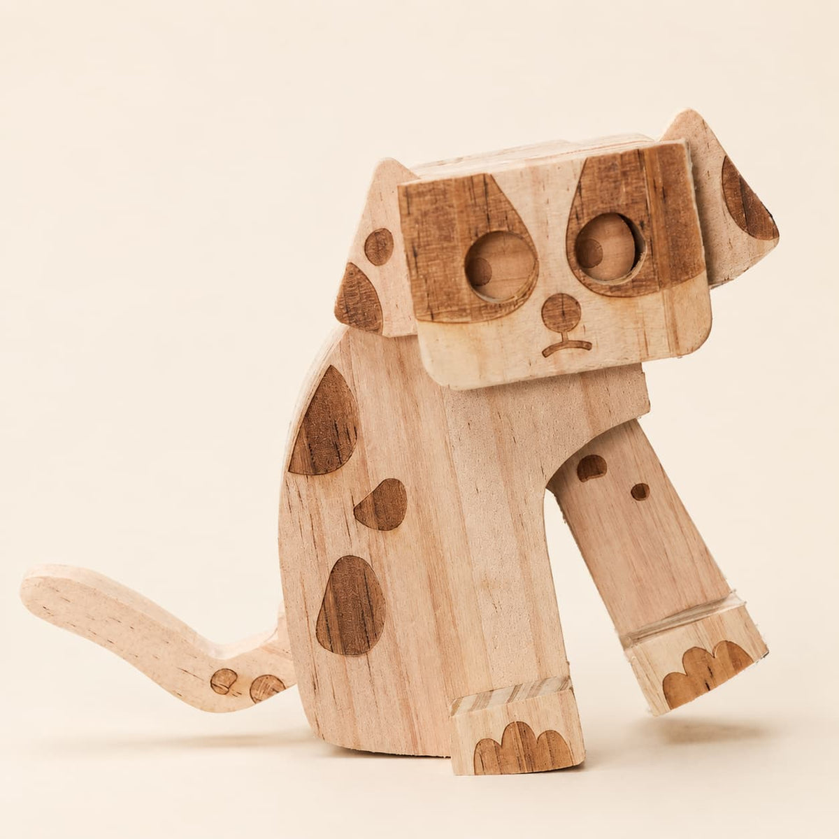 Close-up of a handmade wooden dog ramp walker toy with dark wood spots, carved paws and tail.
