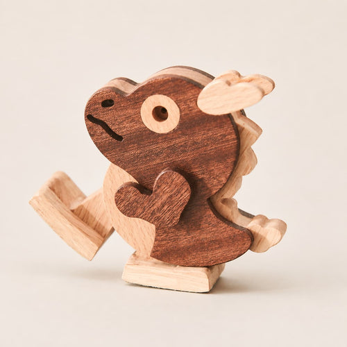 A small wooden dragon toy with a dark brown body and light natural wood accents, photographed on a plain light beige background.