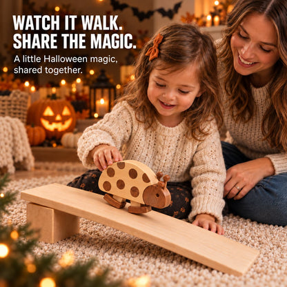 A wooden ladybug ramp walking toy slides on a small wooden ramp while a young child and an adult sit on a carpeted floor in a cozy, warmly lit Halloween-themed room. Text on the top left reads, 'WATCH IT WALK.