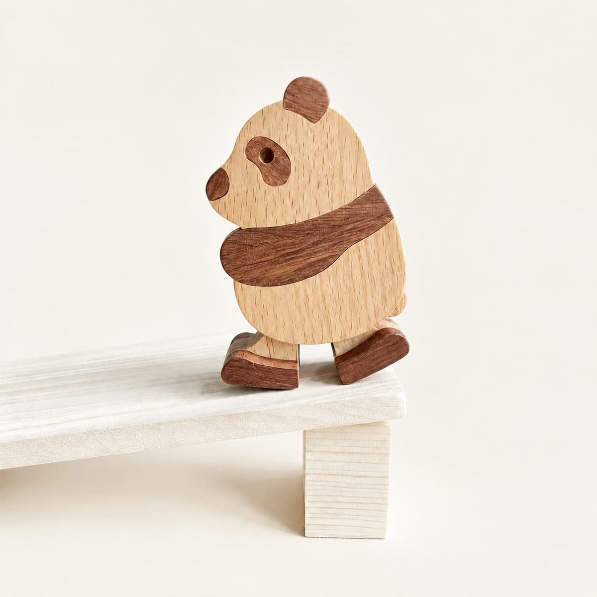 Wooden panda ramp walker toy stepping down a white wooden ramp.