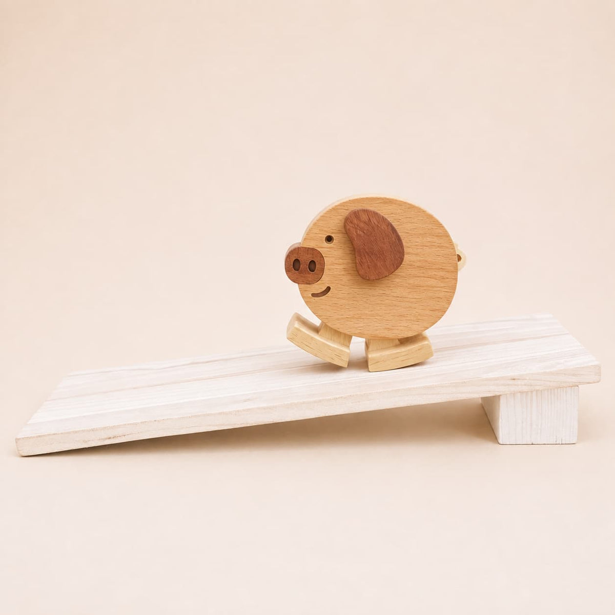 Handmade wooden pig ramp walker toy with dark wood ear and snout details on a gently sloped wooden ramp.