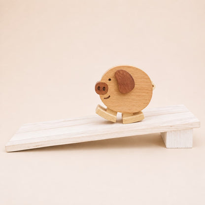 Handmade wooden pig ramp walker toy with dark wood ear and snout details on a gently sloped wooden ramp.