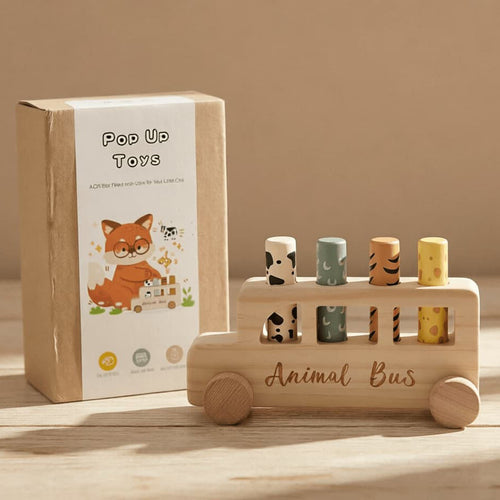 Wooden toy bus with animal shapes and packaging labeled 'Pop Up Toys' on a wooden surface.