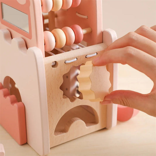 Wooden educational toy with gears and beads, hand interacting with it on a light background