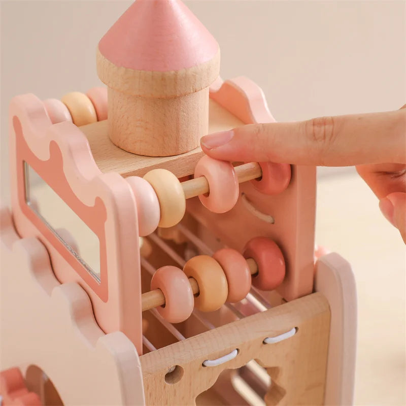 Wooden toy with pink and beige elements, held by a hand against a light background