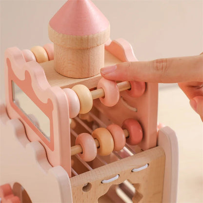 Wooden toy with pink and beige elements, held by a hand against a light background