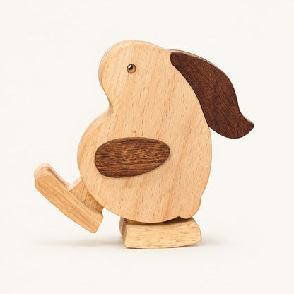A wooden toy rabbit with a light natural wood body, dark brown wing and ear accents, and a small metal eye, shown on a plain light background.