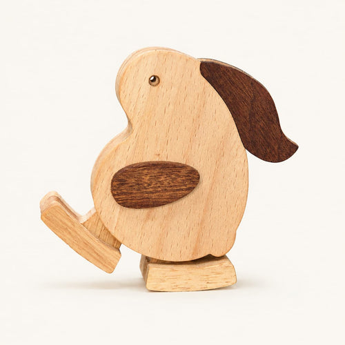A wooden toy rabbit with a light natural wood body, dark brown wing and ear accents, and a small metal eye, shown on a plain light background.