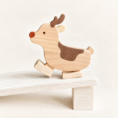Wooden reindeer ramp walker toy with one curved foot raised on a wooden ramp supported by a block.